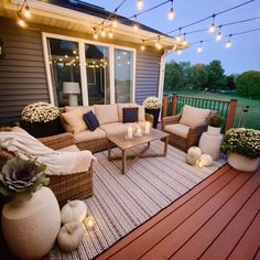 an outdoor patio with wicker furniture and string lights strung over the back deck area