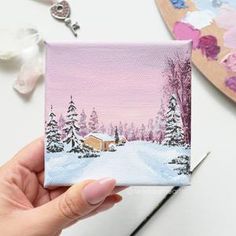 a person holding up a small card with a snowy scene on the front and side