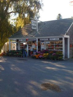 a small store with lots of flowers on the front and side of it's building