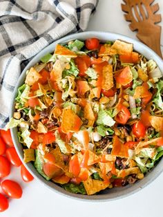 a salad in a bowl with tomatoes, lettuce and other vegetables on the side