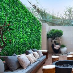 an outdoor living area with couches, tables and potted plants on the wall