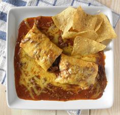 a white plate topped with chicken enchilada and tortilla chips