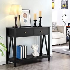 a black table with two candles and pictures on it next to a white couch in a living room