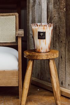 a candle sitting on top of a wooden stool next to a bed