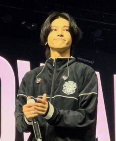 a man standing on top of a stage with his hands folded in front of him