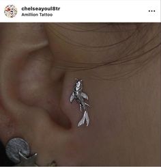 an ear piercing with a bird design on the top and bottom of its ear is shown