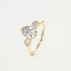 a yellow gold ring with three pear shaped diamonds on the side and an oval diamond in the middle