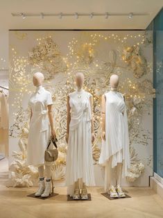 three mannequins are dressed in white dresses and holding handbags while standing next to each other