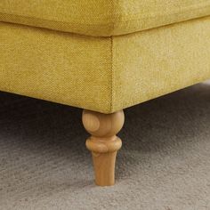 a close up view of the bottom of a yellow couch with wood legs and feet