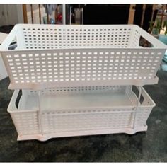 a white plastic basket sitting on top of a counter next to a shelf with baskets