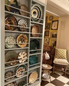 a room filled with lots of plates on shelves next to a checkerboard floor