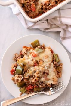 a casserole dish filled with ground beef and vegetables on a plate next to a fork