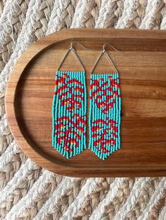 two pairs of beaded earrings sitting on top of a wooden tray