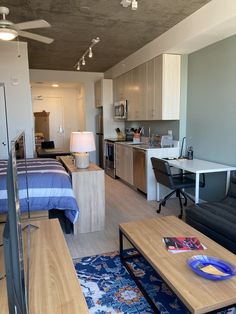 a living room filled with furniture next to a kitchen and dining area in front of a bed