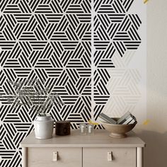 a white dresser sitting next to a wall with black and white designs on it's sides