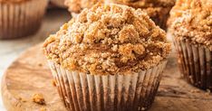 several muffins are sitting on a wooden board with crumbs all over them