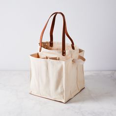 a canvas tote bag with leather handles on a marble countertop in front of a white wall