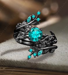 a black gold ring with blue topaz and leaves on the sides, sitting on a book