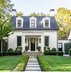 a white house with black shutters and two story windows on the front, grass lawn in front