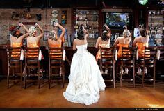 a group of women sitting at a bar with their arms in the air and one woman standing