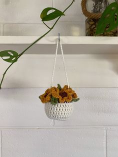 a white hanging basket with sunflowers in it