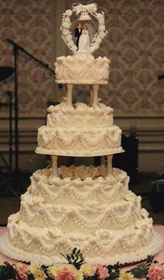 a three tiered wedding cake with flowers on the table