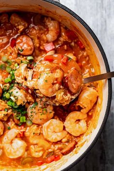 a large pot filled with shrimp and red pepper sauce on top of a wooden table