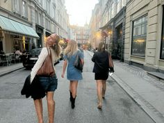 three women walking down the street in front of buildings