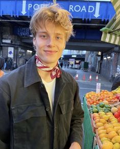 a young man standing in front of a fruit stand