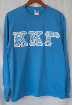 a blue long sleeve shirt with the letters k & f printed in white on it