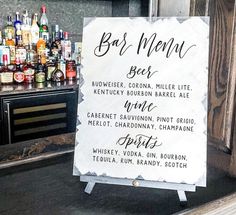 a bar menu sitting on top of a wooden table next to a shelf filled with bottles