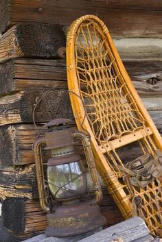 an old chair and lantern sitting on top of a pile of books next to a wooden wall