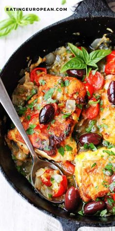 a skillet filled with meat and vegetables on top of a white table next to a spoon