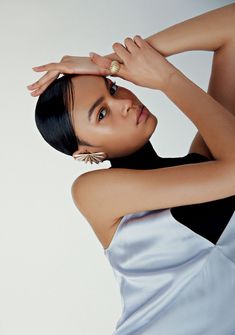 a woman in a black and white dress with her hands on her head