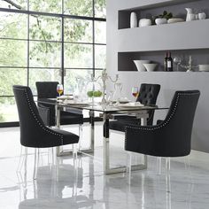 a glass table with black chairs and plates on it