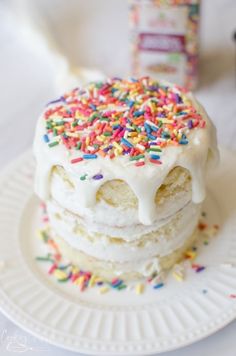 a white plate topped with cake covered in frosting and sprinkles