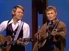 two men are playing guitars and singing into microphones on the set of an old tv show