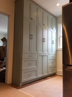 an empty kitchen with white cabinets and stainless steel refrigerator