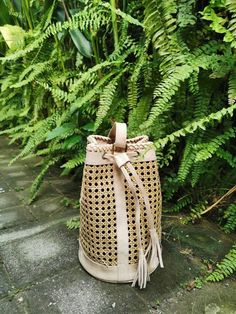 Handwoven natural rattan meets premium leather in this beautifully designed bucket bag. Free shipping available on all rattan bags. Crafted from stamped leather and rattan, this small bucket bag combines minimalist design with timeless appeal. Features a removable strap and detachable handle for versatile wearability, allowing you to style it according to your mood. Spacious enough to carry all your essentials, it includes a leather drawstring strap for secure closure. The tropical backpack showcases leather detailing and cane webbing, offering a sophisticated yet casual look. Ideal for vacations, its natural elements bring a touch of elegance to your travels. Each backpack is meticulously handmade by Balinese artisans. Dimensions: 21 cm high / 17 cm wide. Orders take approximately seven d Metallic Cowhide Rug, Wood Carrier, Rattan Bags, Brindle Cowhide, Patchwork Cowhide Rug, Leather Toiletry Bag, Real Leather Bags, Cowhide Bag, Life Nature