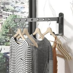 three shirts are hanging on a rack in front of a window