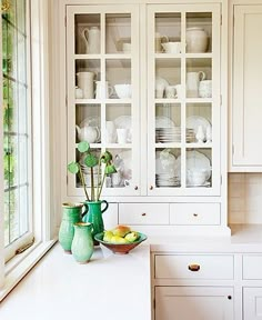 a kitchen with white cabinets and green vases