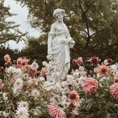 there is a statue in the middle of a garden with pink and white flowers around it