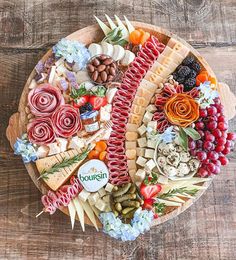 a wooden platter filled with different types of cheese and meats