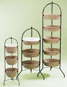 three tiered baskets are on display in front of a green wall and black iron stand