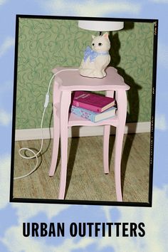 a white rabbit sitting on top of a pink table next to a pile of books