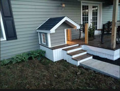 a dog house sitting on top of steps next to a porch with stairs leading up to it