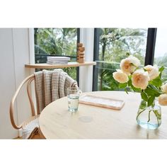 a vase filled with flowers sitting on top of a wooden table next to a window