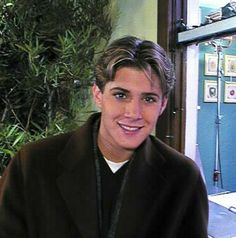 a man sitting at a table in front of a laptop computer and smiling for the camera