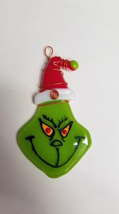 a green glass ornament with a red santa hat on it's head