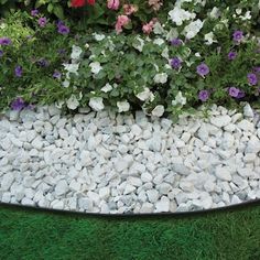 flowers and rocks in a garden bed on the grass, with green grass around them